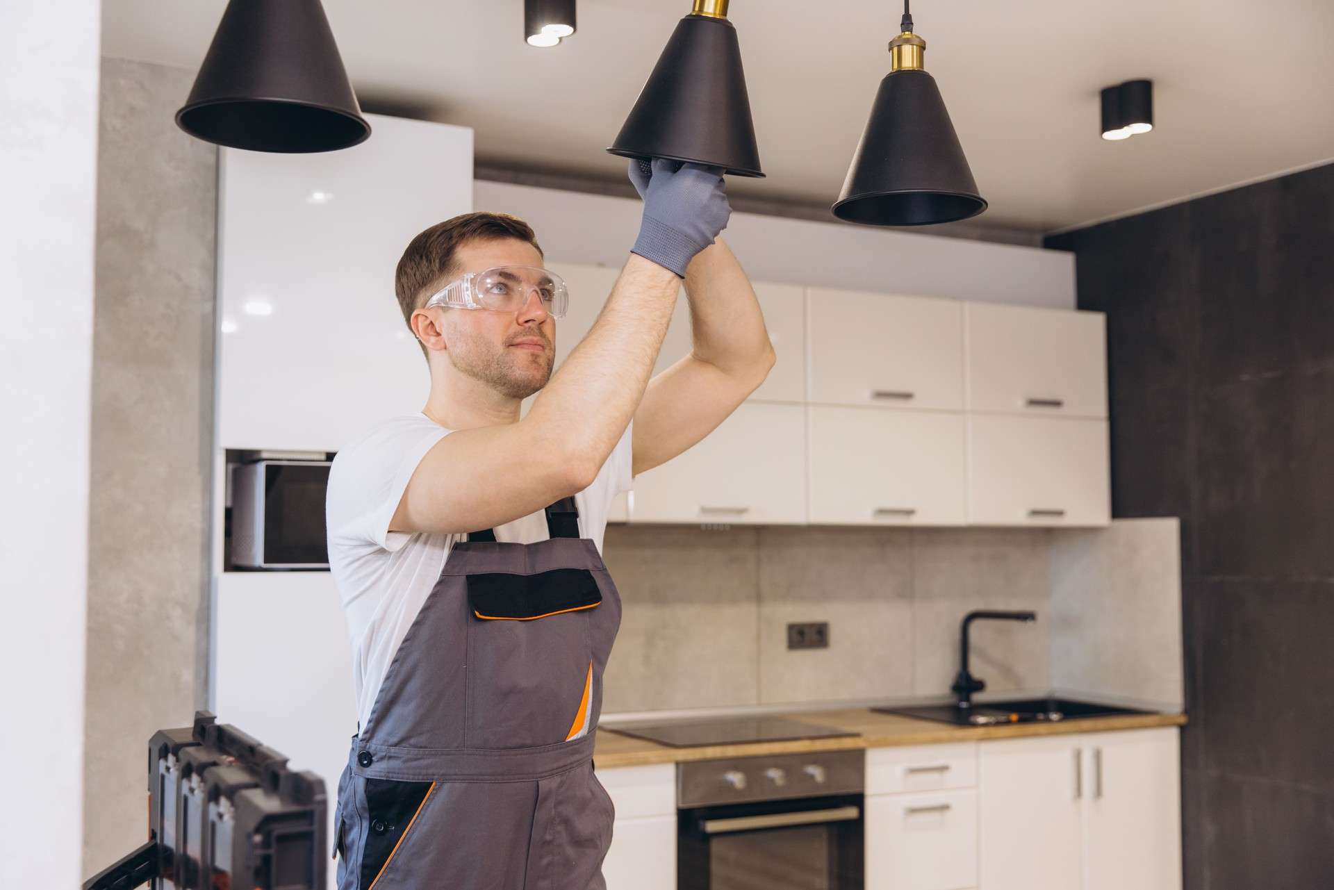 Electrician installing pendant lamps in a modern kitchen